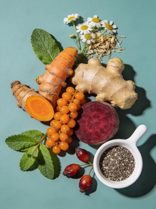 Assorted health foods including turmeric, ginger, carrots, berries, and chia seeds on a teal background